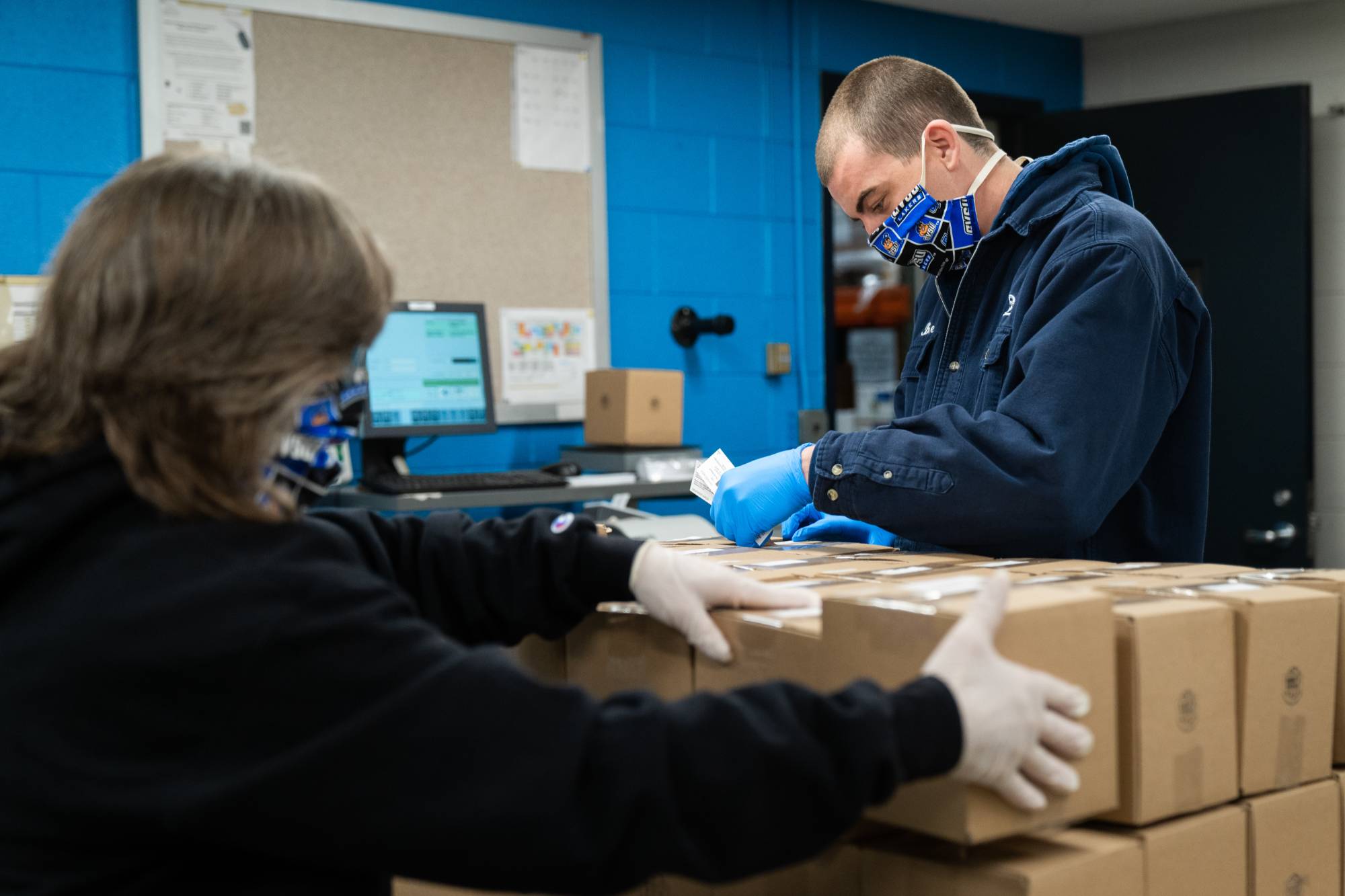 Two mailroom staff packaging boxes